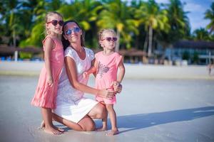 madre y sus lindas niñas relajándose en una playa tropical exótica foto