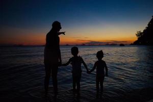 familia de tres siluetas al atardecer en la playa de boracay foto