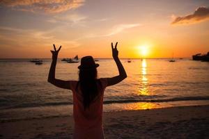 silueta de una mujer joven con las manos levantadas al atardecer en la isla boracay, filipinas foto