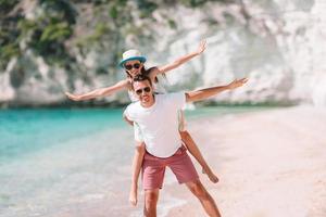 Little girl and happy dad having fun during beach vacation photo