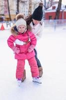 joven madre y su linda hijita en una pista de patinaje foto