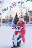 Adorable little girl skating on the ice-rink photo