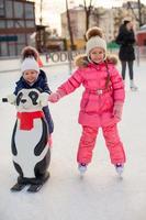 dos adorables niñas patinando en la pista de hielo foto