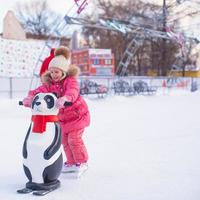 Adorable little girl skating on the ice-rink photo