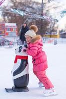 Adorable little girl skating on the ice-rink photo