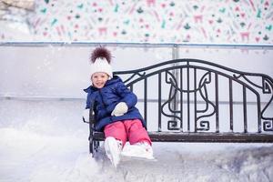 niña sentada en un banco en la pista de patinaje foto