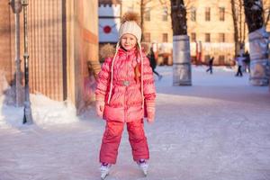 Adorable little girl skating on the ice-rink photo