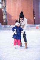 niña adorable con su mamá aprendiendo a patinar foto