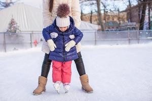 niña adorable con su mamá aprendiendo a patinar foto