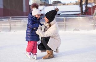 joven madre y su linda hijita en una pista de patinaje foto