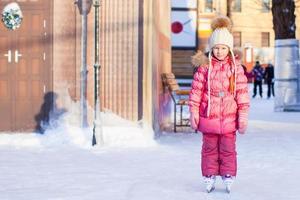 Adorable happy little girl enjoying skating at the ice-rink photo