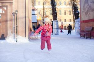 Adorable happy little girl enjoying skating at the ice-rink photo