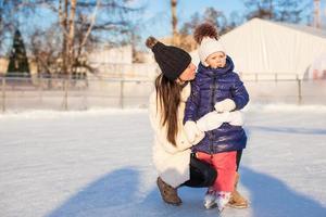 joven madre y su linda hijita en una pista de patinaje foto