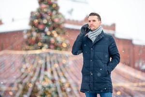 Happy man near fir-tree branch in snow for new year. photo