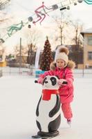 Adorable little girl skating on the ice-rink photo