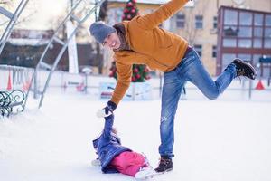 Father with his daughter skates on ice skating in the winter. photo