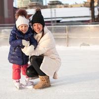 sonriente joven madre y su linda hijita patinando sobre hielo juntos foto