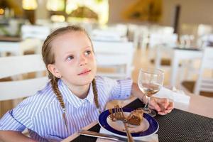 Adorable little girl having breakfast at resort restaurant photo