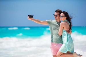 Happy couple taking a photo on a beach on holidays