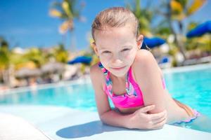 Portrait little girl having fun in outdoor swimming pool photo