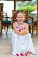 adorable niña con jugo en un café al aire libre foto