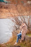 Fall concept - beautiful woman in autumn park under fall foliage photo