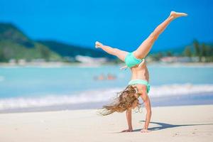 Adorable active little girl at beach during summer vacation photo