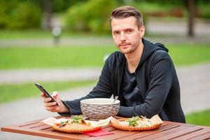 joven comiendo fideos para llevar en la calle foto