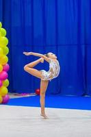 Beautiful little gymnast girl on the carpet on the competition photo