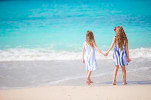 Adorable little girls walking on the beach photo