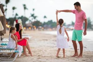 Parents and adorable two kids have a lot of fun during their summer vacation on the beach. Family of four in love, happy and beautiful. photo