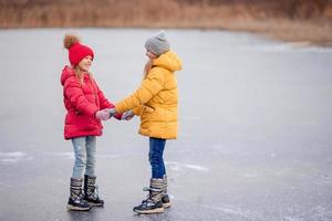 Adorable little girls skating on the ice-rink photo