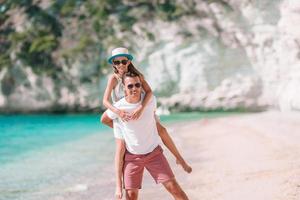 Little girl and happy dad having fun during beach vacation photo