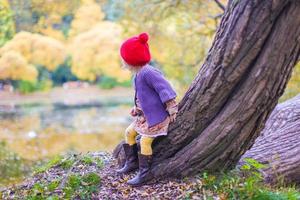 Cute little girl in a red cap near lake at the autumn park photo