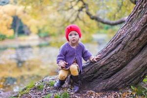 Little cute girl in red hat having fun at autumn park photo