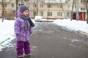 linda niña feliz caminando en la nieve en un soleado día de invierno al aire libre foto