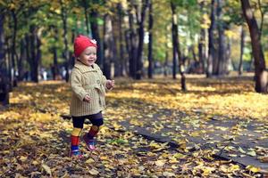 Little beautiful girl walking in autumn park photo