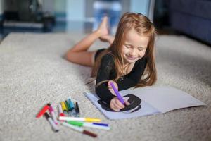 Portrait of a sweet charming young girl who draws with his coloring at home photo