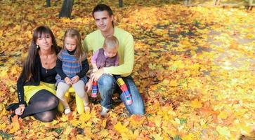 Young charming family of four enjoying the weather in yellow autumn park photo