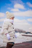 Little cute happy girl is walking in the snow on a sunny winter day photo