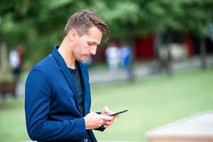 el hombre está leyendo un mensaje de texto en el teléfono móvil mientras camina en el parque