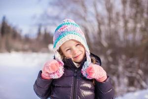 retrato de una niña adorable con sombrero de invierno en un bosque nevado foto