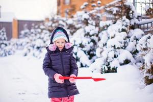 Little girl playing with red shovel in the garden photo