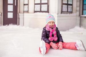 niña adorable sentada en el hielo después de la caída foto