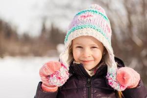 retrato de una adorable niña feliz en el soleado día de invierno nevado foto