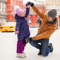 el padre joven y la niña adorable se divierten en la pista de patinaje foto
