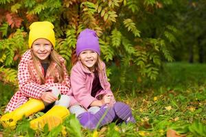 Two adorable girls in forest at warm sunny autumn day photo