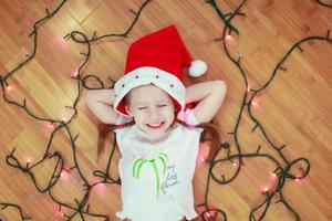 Little happy girl lies among the multi-colored lights on a wooden floor photo