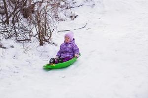 adorable niña en trineo en el bosque nevado foto