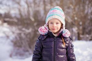 Portrait of little adorable girl in winter hat at snowy forest photo